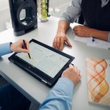 Zwei Personen sitzen sich gegenüber und schauen auf ein Tablet